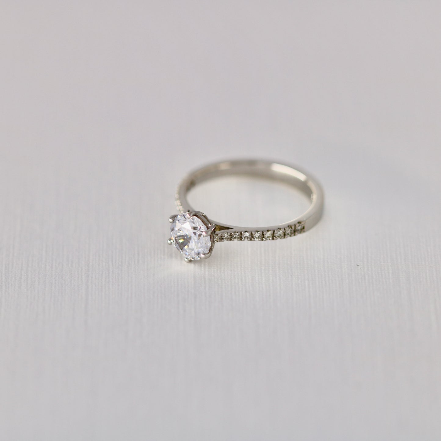 Six claw solitaire with diamonds in band